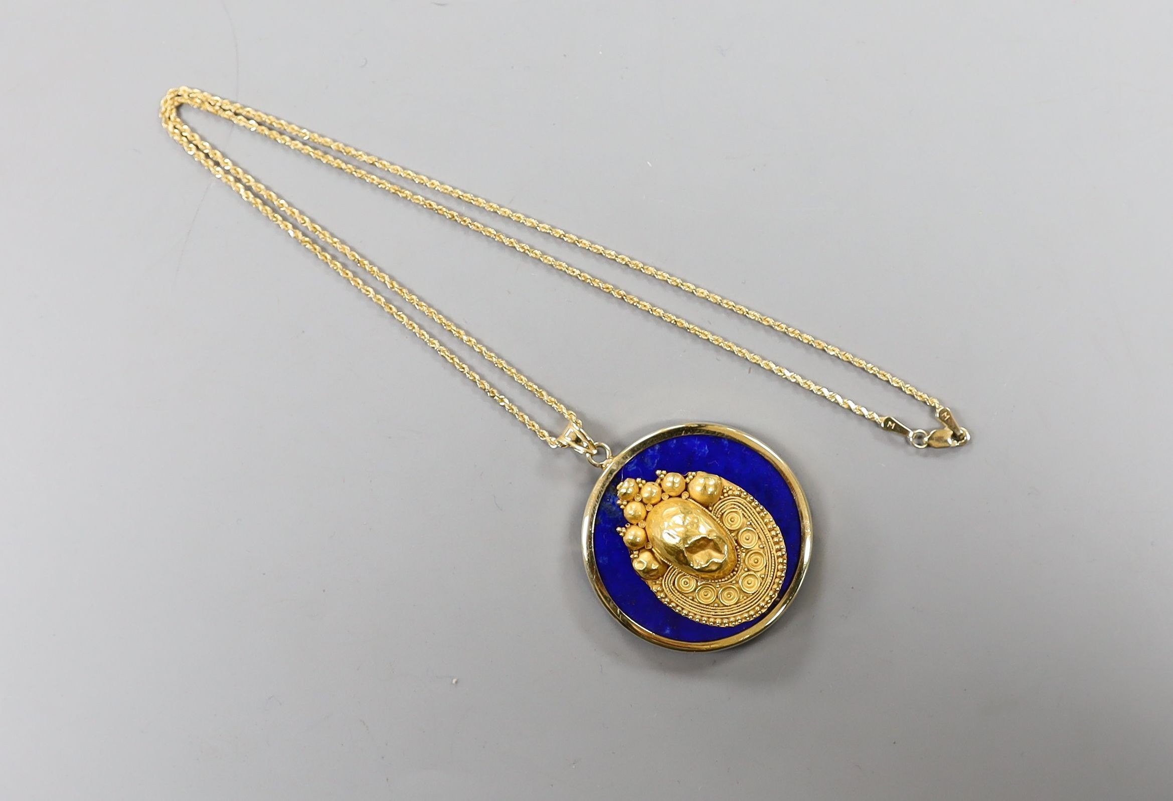 An Egyptian yellow metal earring from the Josephine Dubois Collection, now mounted on a 14l and lapis lazuli circular pendant, with a 14k chain